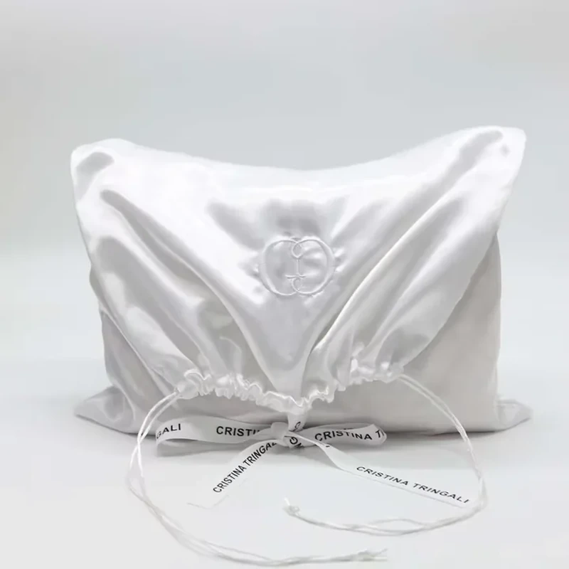 A square satin body gathers at a wide opening with long cords and ribbon detail