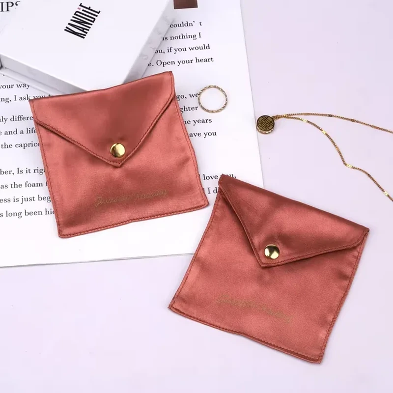 A stitched square satin pocket closes with a pointed flap and small metal snap
