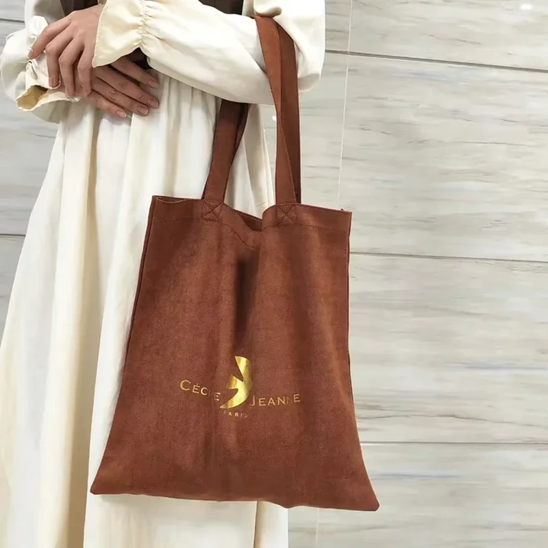 Long narrow handles extend from a tall unstructured tote with a simple flat body