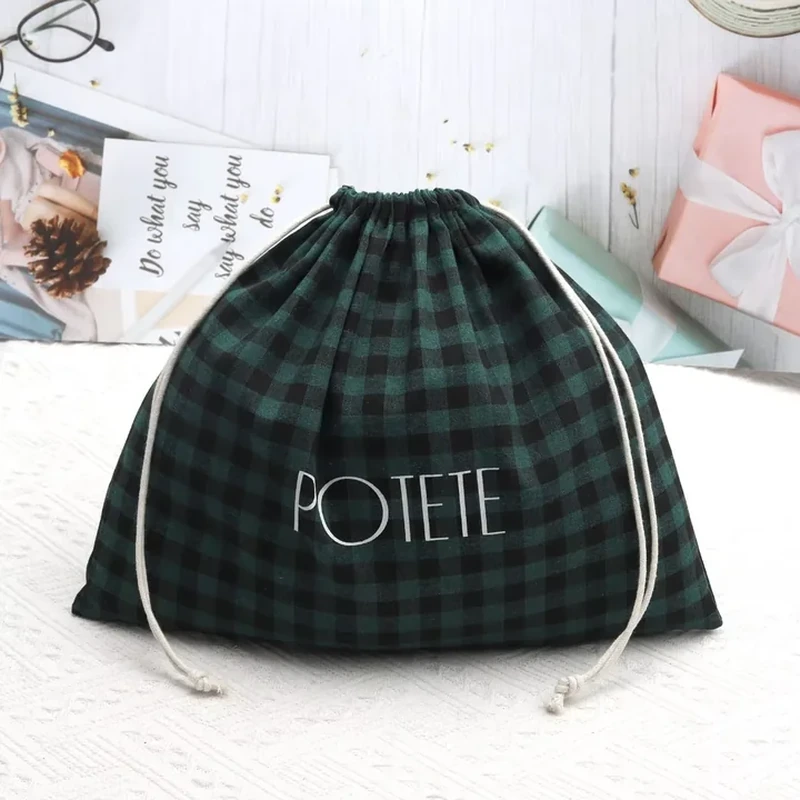 A rounded drawstring sack has a dark tartan pattern and contrasting pale cords