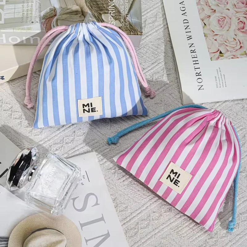 A compact gathered bag has bold vertical stripes and a small rectangular front label