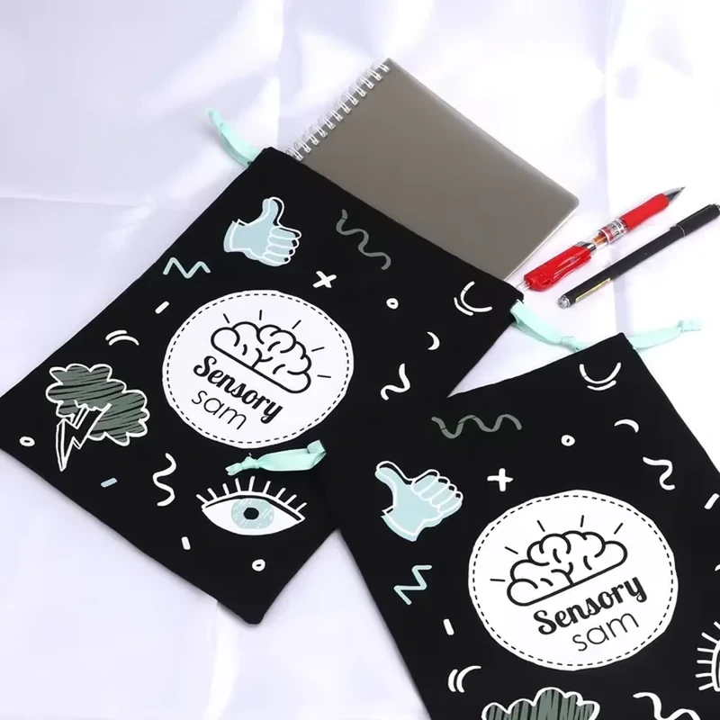 A dark drawstring pouch is covered with pale doodles, small stars and playful line graphics