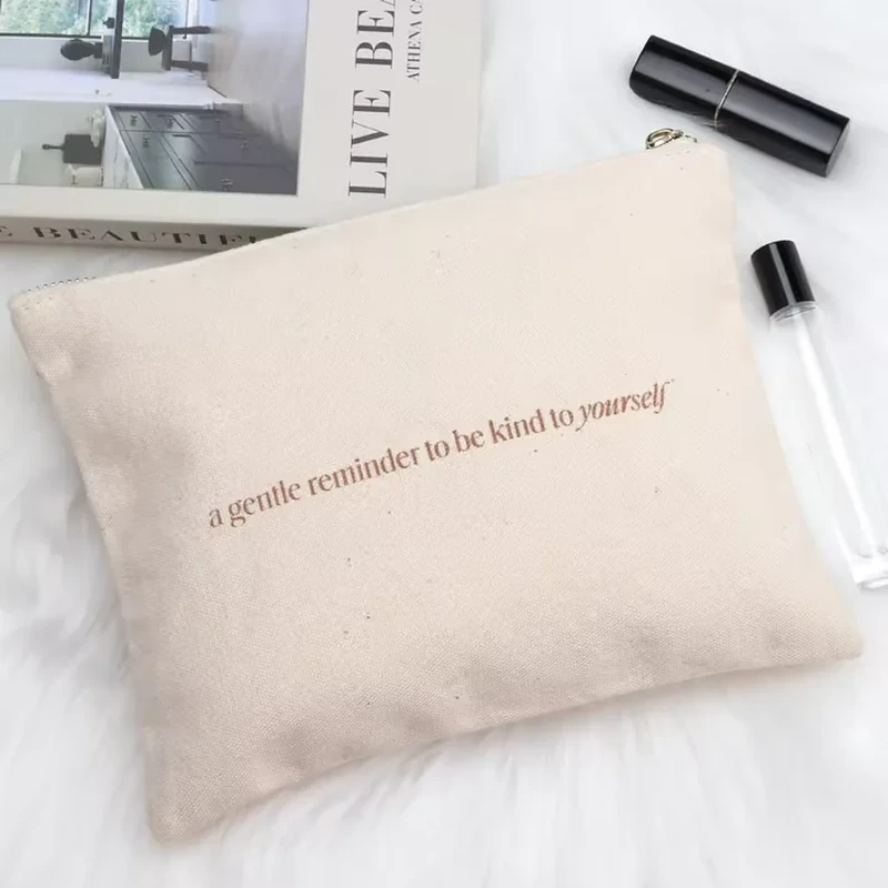 A wide cream pouch has a straight zipper opening and a simple horizontal text layout