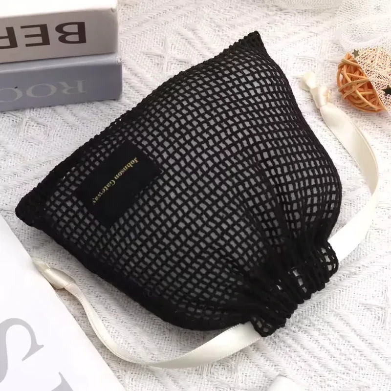 Black wide-net beauty pouch with cream ribbon ties and a small front label