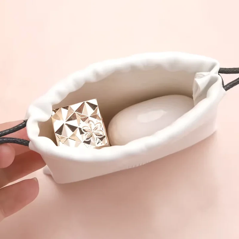 Open pale leather-look vanity pouch showing a wide gathered rim and cosmetic items