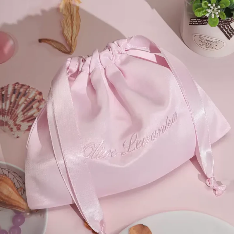 Broad satin ribbons gather a softly rounded pouch and trail down its sides