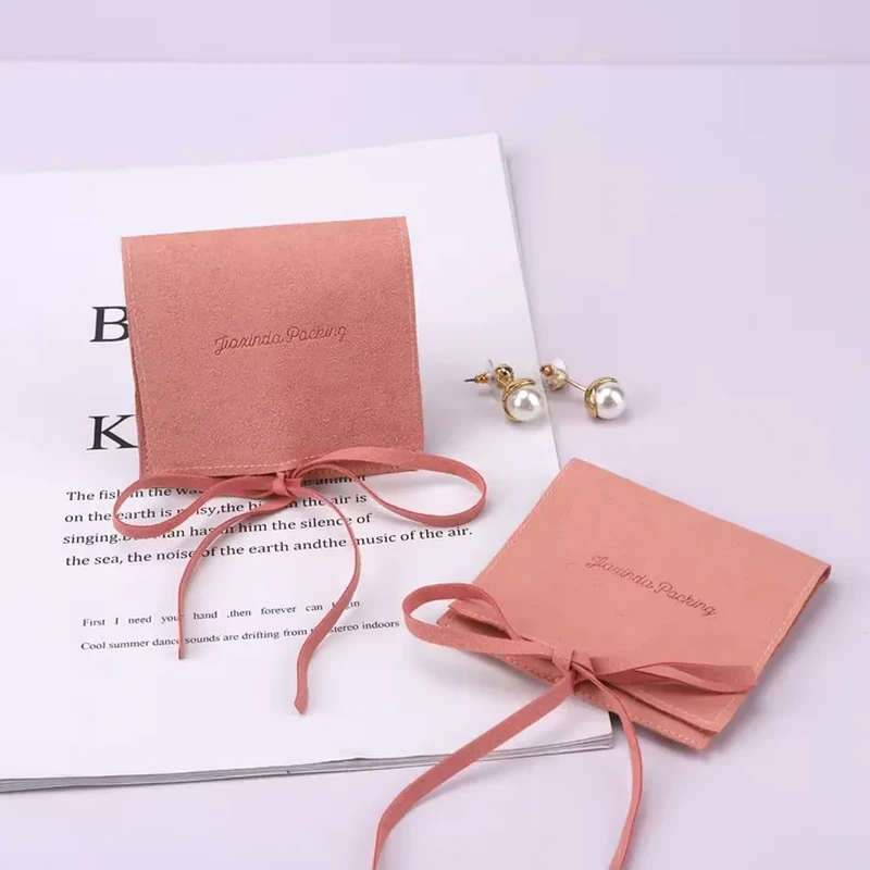 A square folding jewelry folio closes with long narrow ties around its body