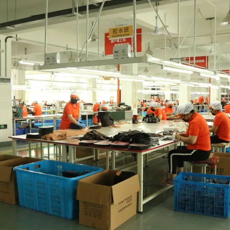 Workers handling bag components at worktables on the production floor.