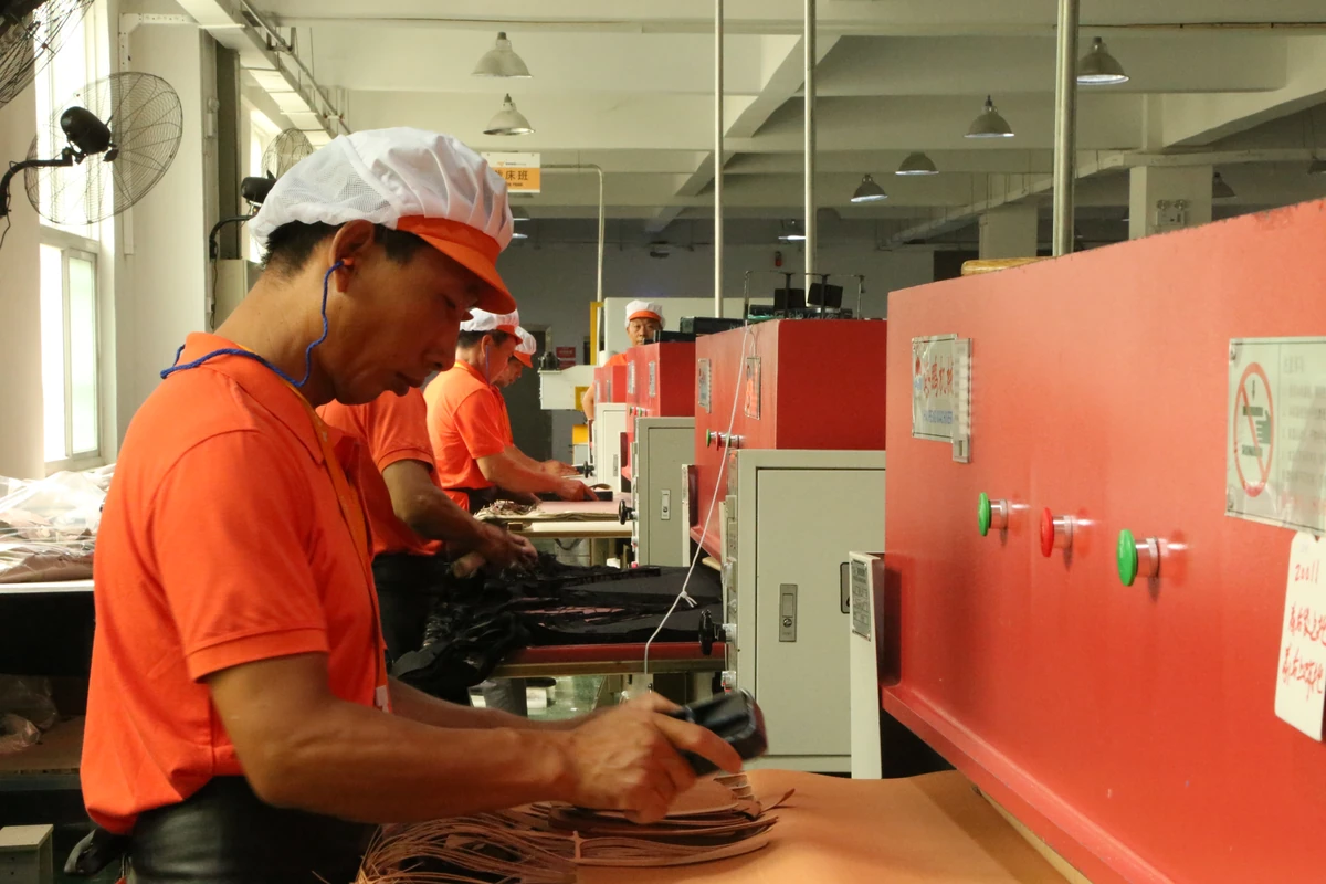 Operators handling bag components at industrial equipment.