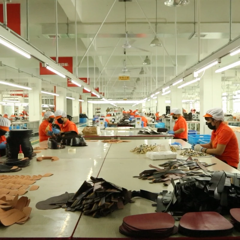 Workers handling pre-cut bag components arranged on long production tables.