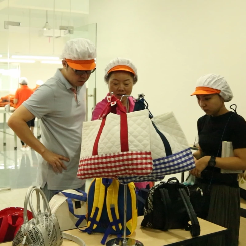 A group looking at bag samples together in a factory sample room.