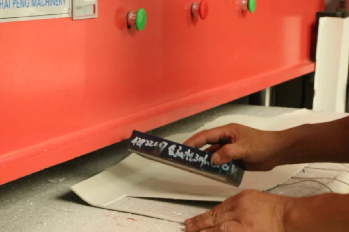 An operator positioning bag components on the table of a material processing machine.