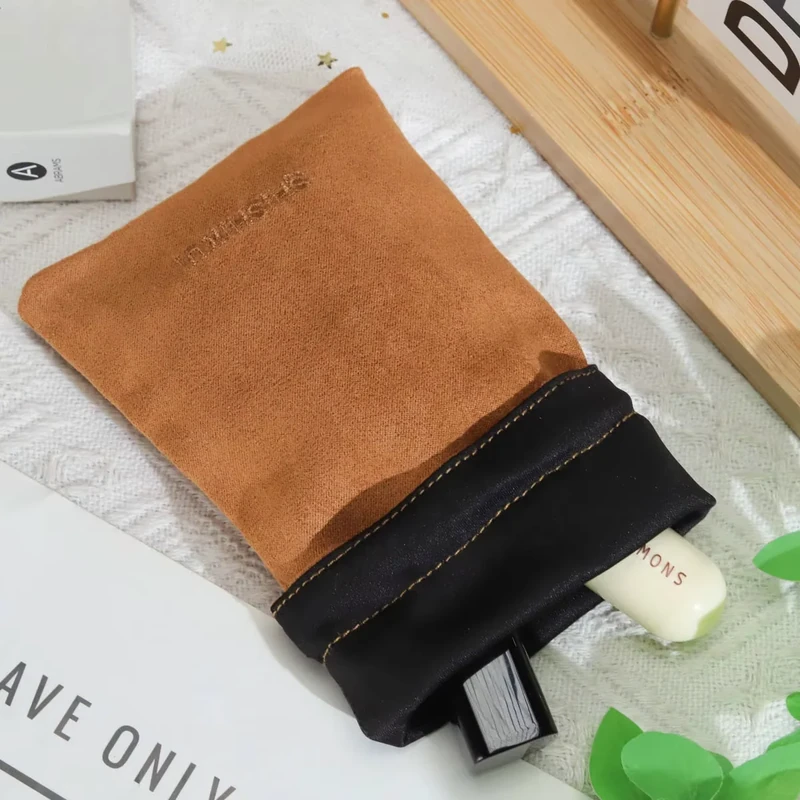 Tan pouch with a black opening and visible stitching, holding cosmetic tubes.