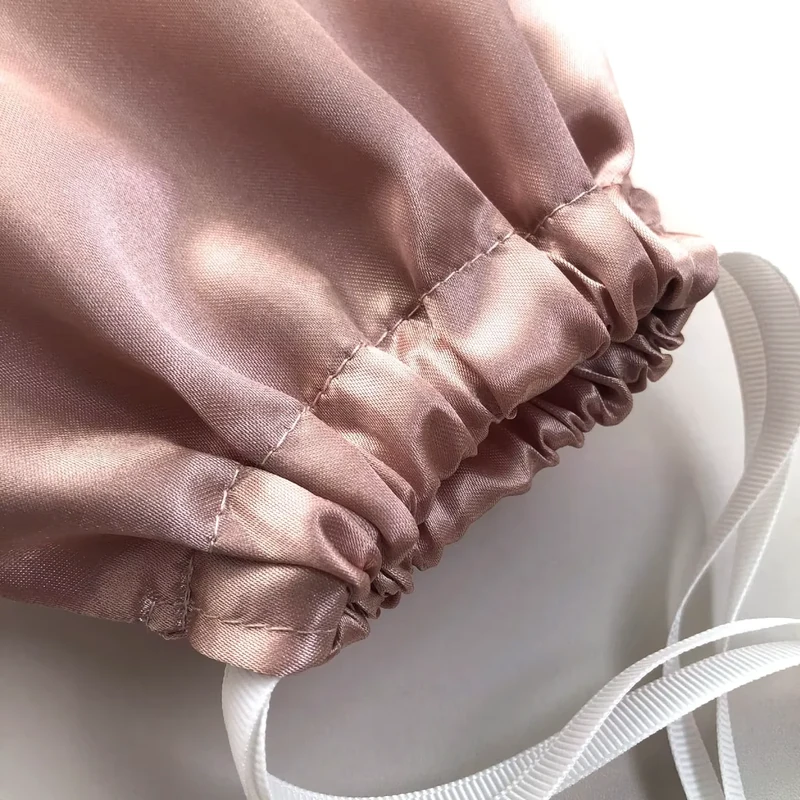 Close-up of a rose-colored gathered fabric channel with pale ribbon