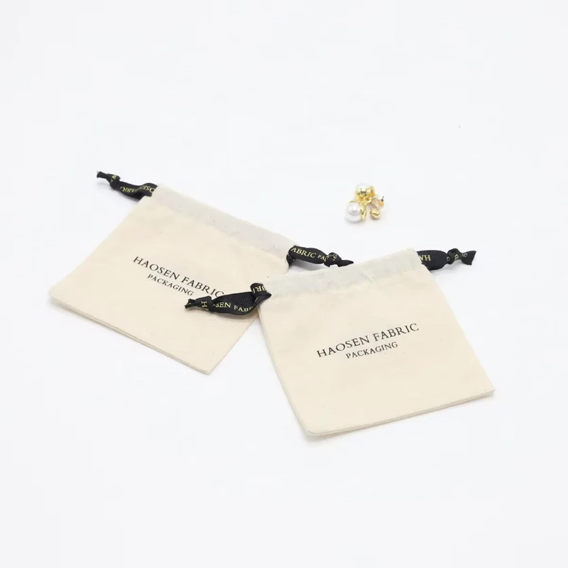 Two cream flat pouches with dark drawstring ties
