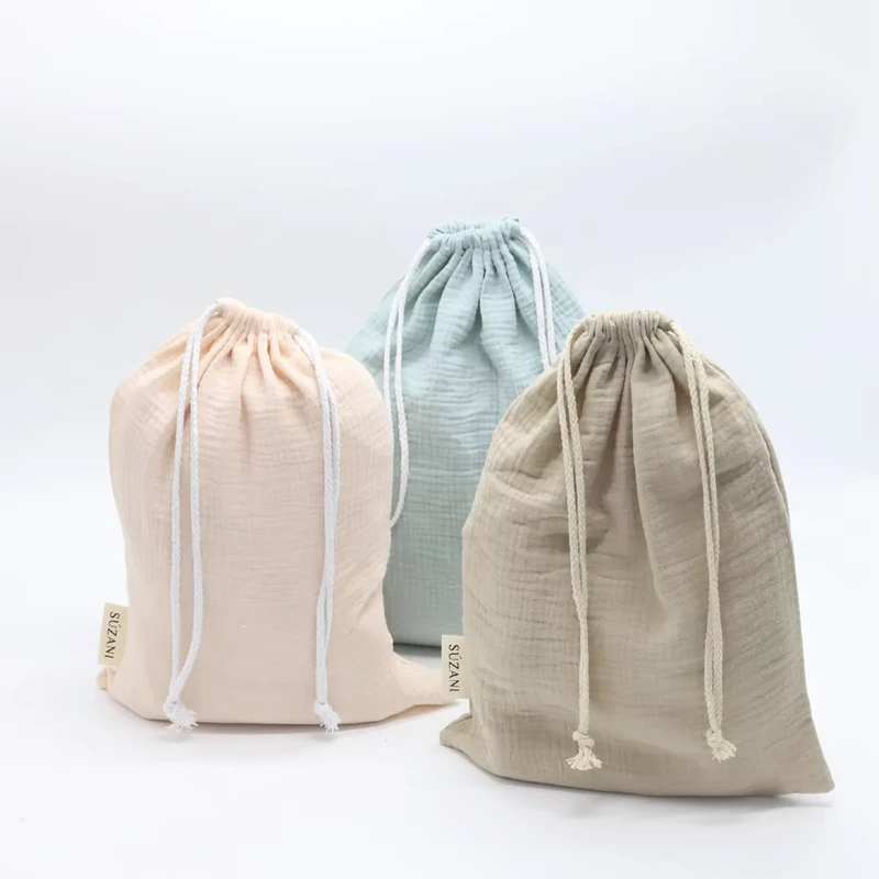 Three drawstring pouches in pale pink, blue and taupe