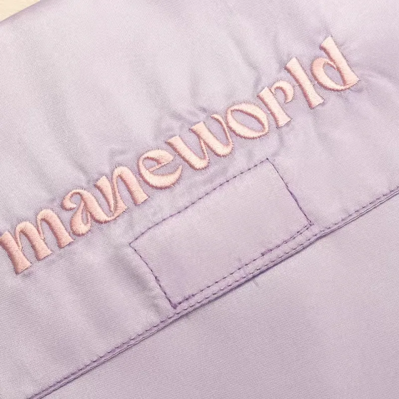 Close-up of raised pale embroidery on lilac fabric
