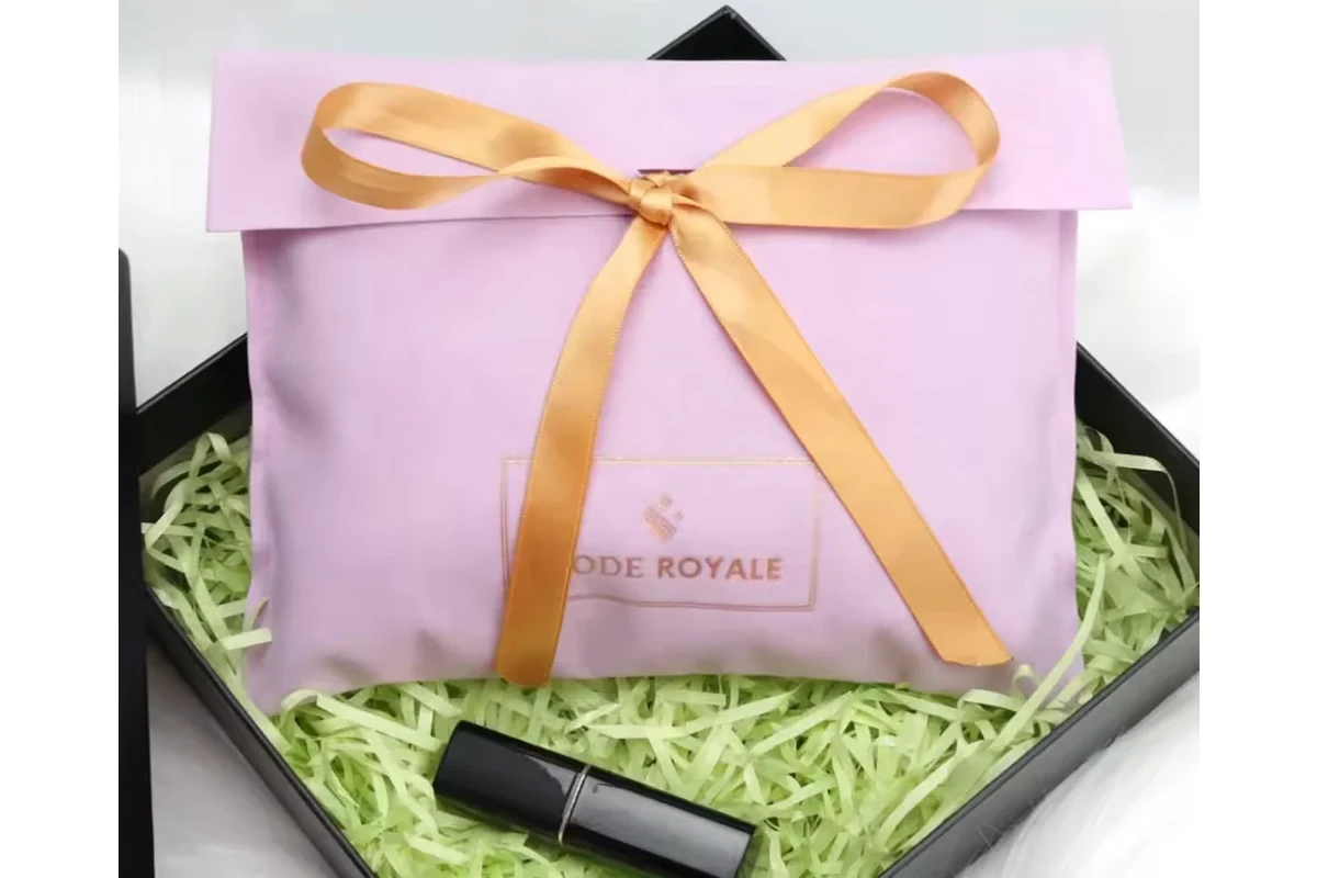 Pink ribbon-tied fabric envelope inside a gift box