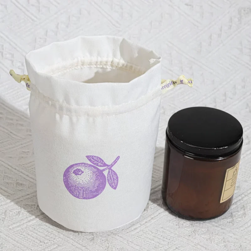 Open round-base fabric pouch beside a brown jar
