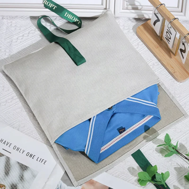 Open light fabric bag holding a folded blue item