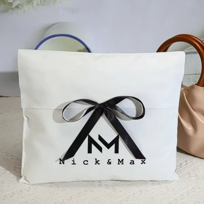 White ribbon-tied fabric dust bag displayed in front of handbags
