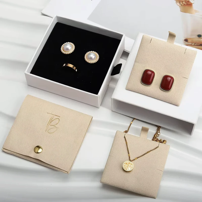 Beige jewelry pouches and display pads arranged with open presentation boxes.