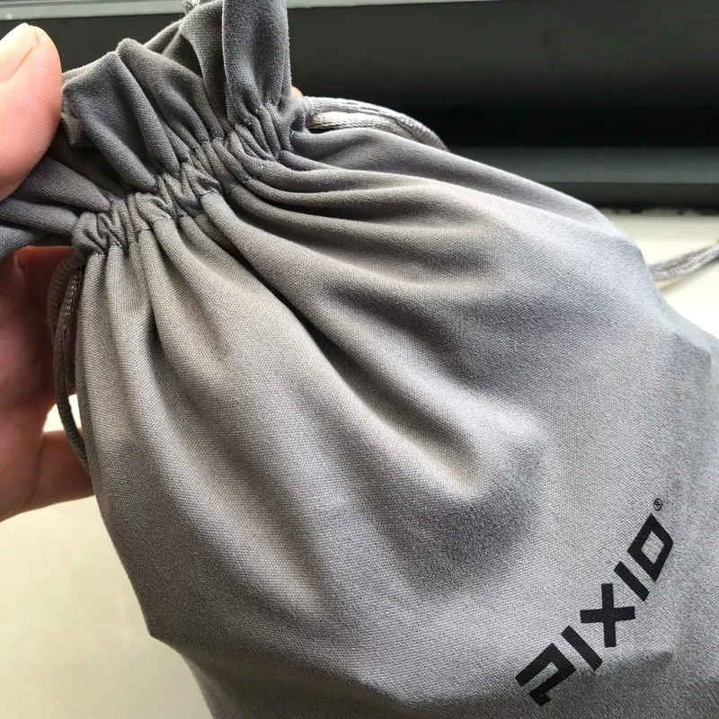 Close-up of a hand gathering the mouth of a gray fabric bag