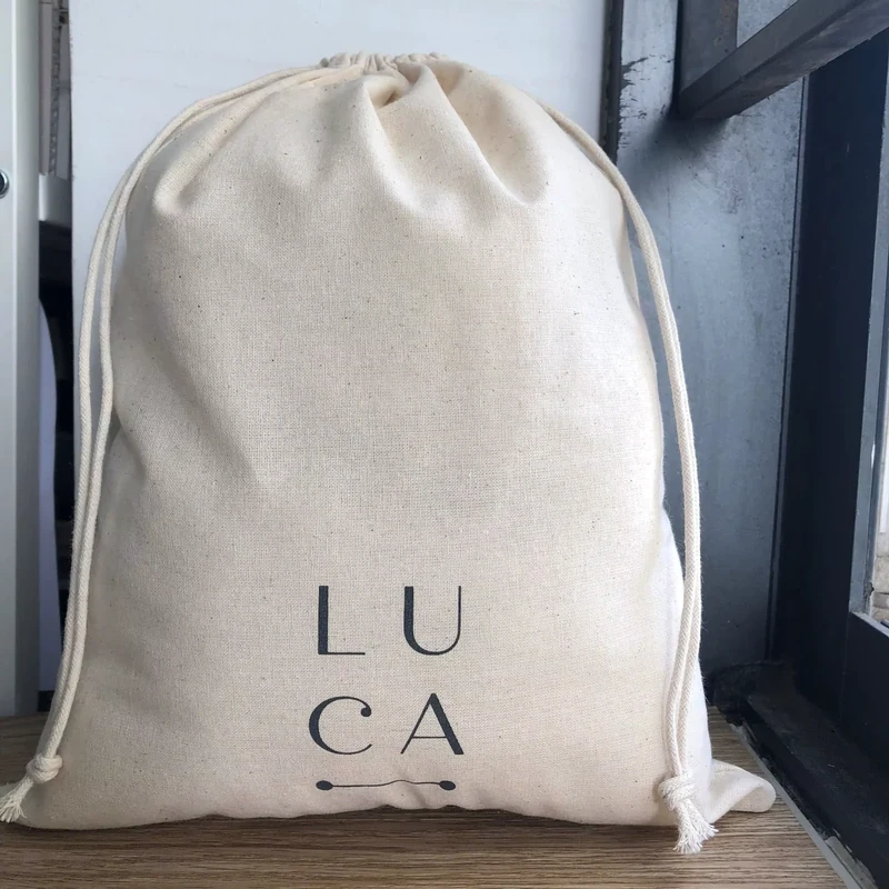 Large pale drawstring bag with a centered lettered logo