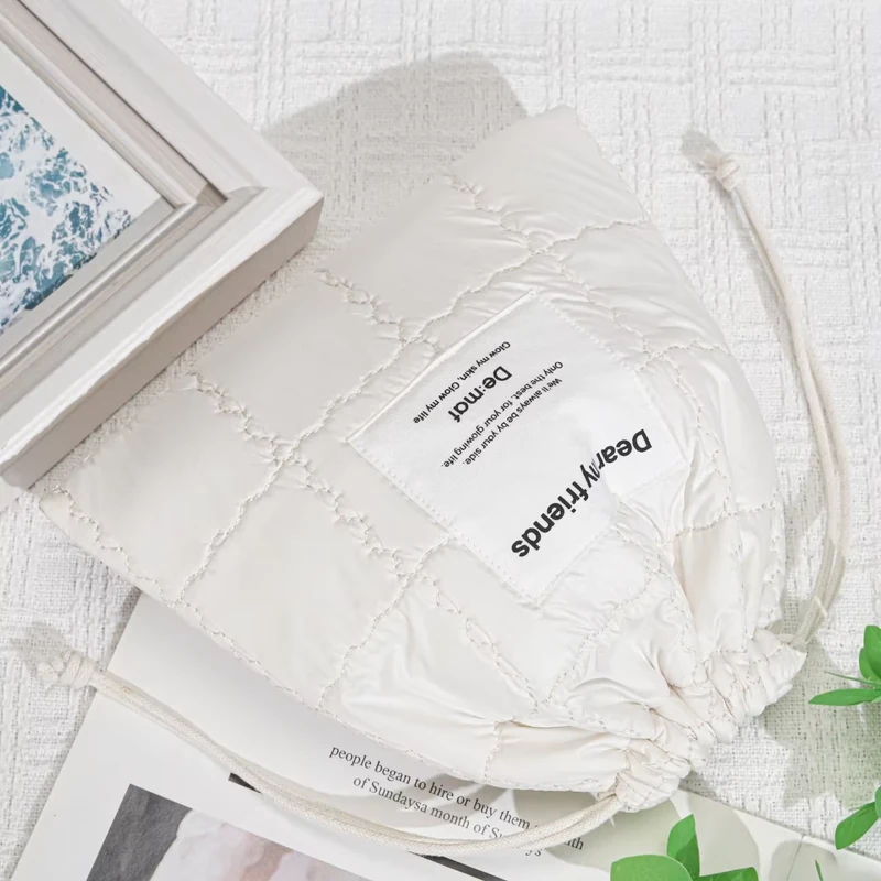 White textured drawstring pouch with a front label