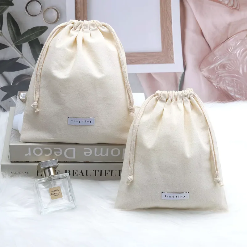 Two ivory drawstring pouches in different sizes with pale cord ties.