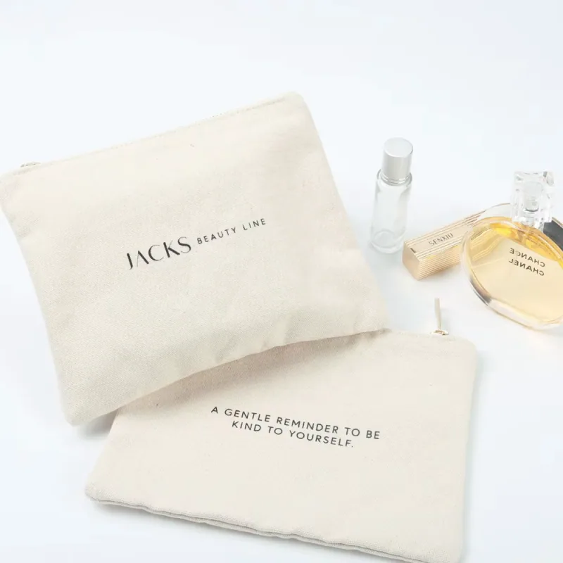 Cream zipper pouches arranged with small beauty accessories.