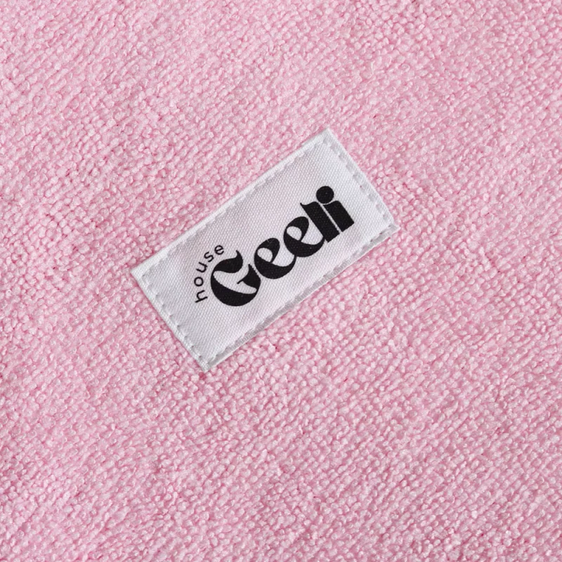 Close-up of a white woven label sewn onto pink looped fabric.