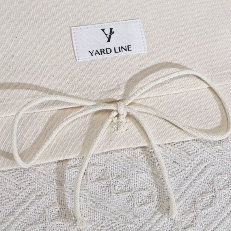 Close-up of natural woven fabric, a sewn label and a pale cord bow.