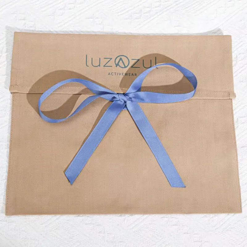 Natural-tone fabric gift envelope tied with a blue ribbon bow.
