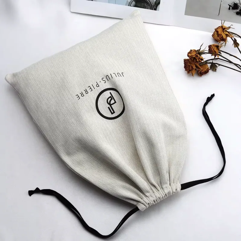 Cream fabric drawstring pouch laid flat with black cords spread to both sides.