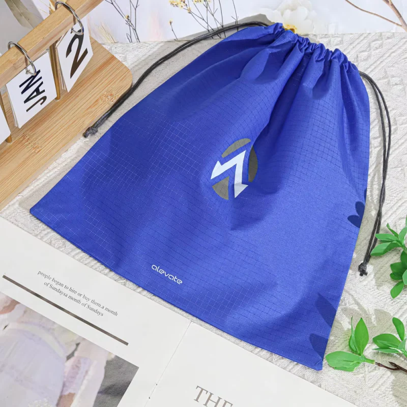 Blue drawstring travel bag laid flat with its cords extended.