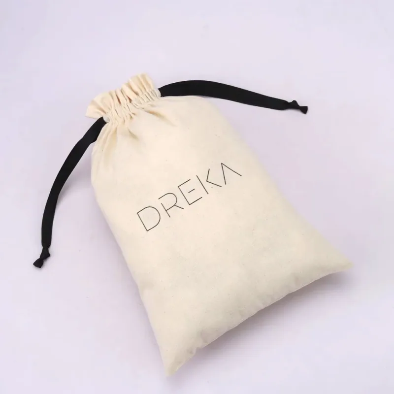 Cream drawstring pouch with black ties extending from both sides.