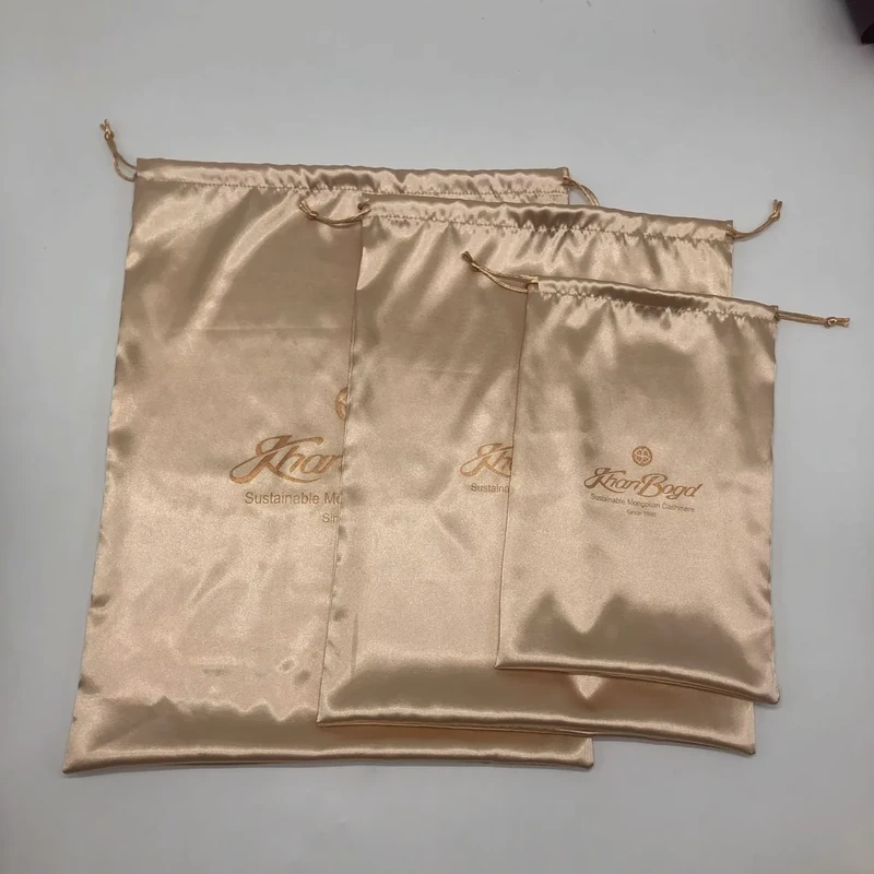 Three champagne-colored drawstring pouches laid flat in different sizes.