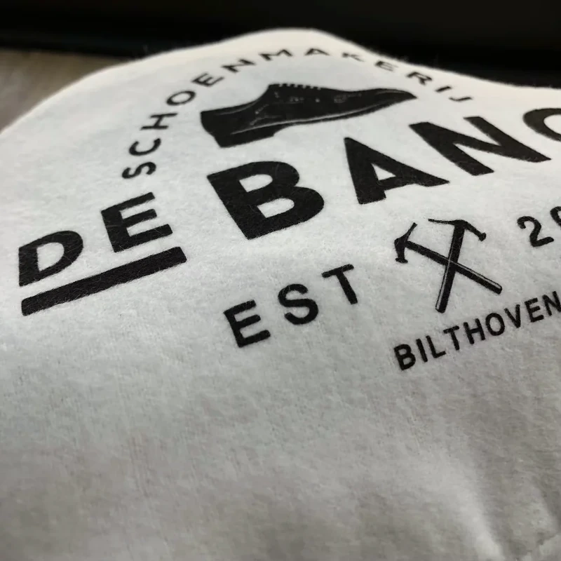Close-up of a bold dark logo on pale fabric.