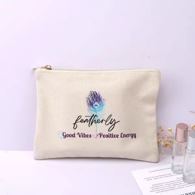 Cream zipper pouch with a colorful peacock-feather motif and script text