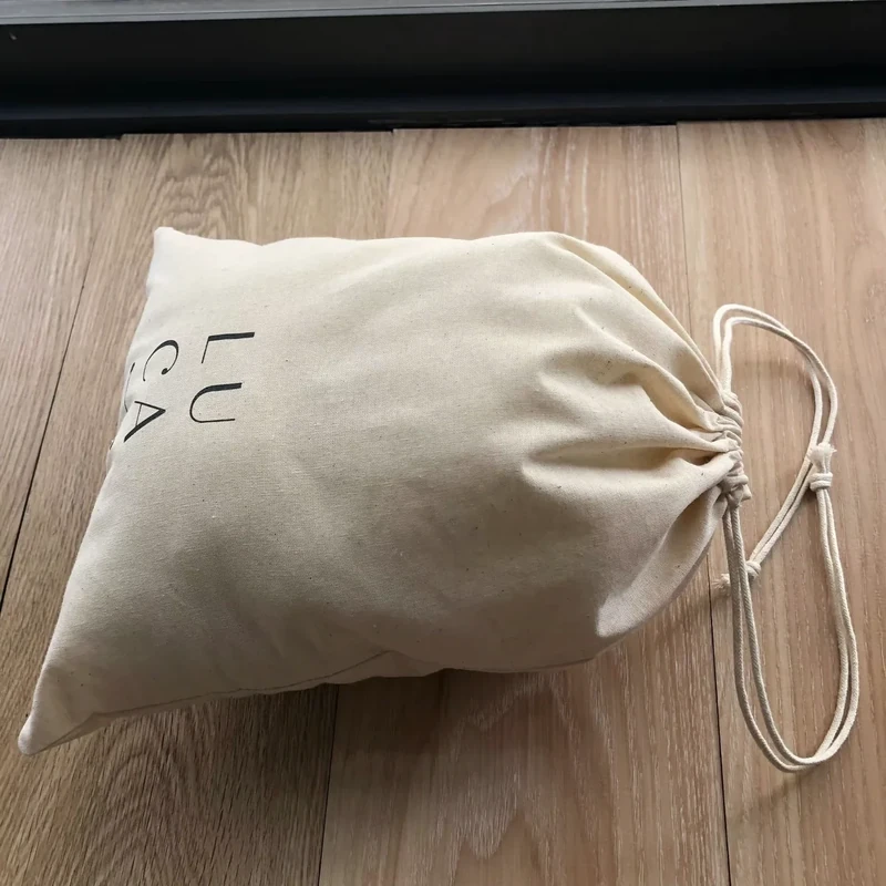 Filled cream drawstring pouch resting on a wooden surface