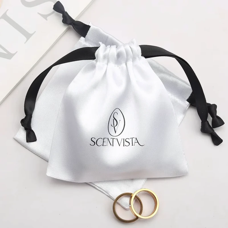 White jewelry pouch with dark ribbon ties emerging on both sides