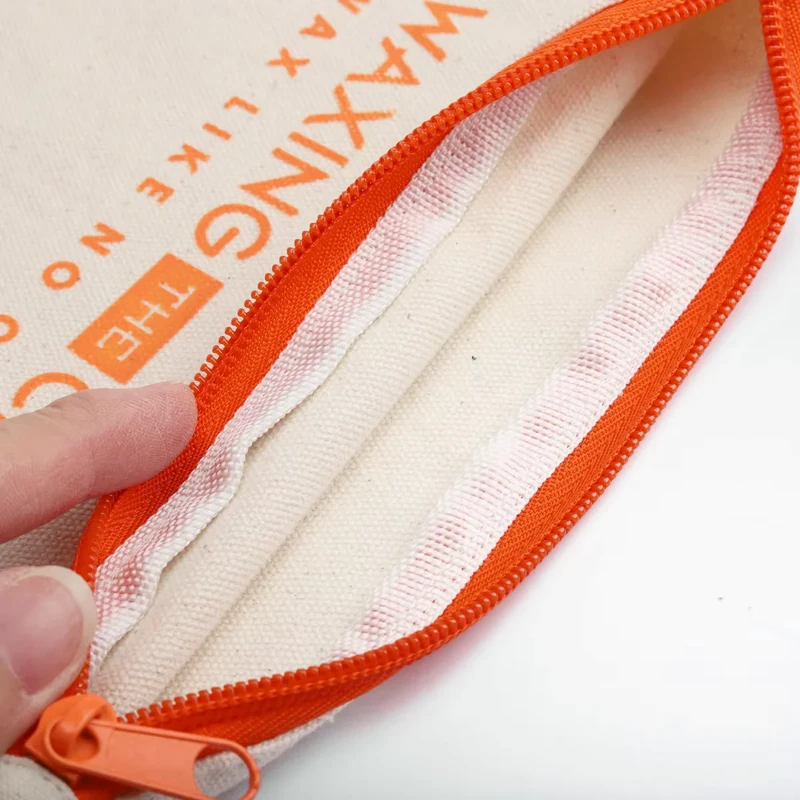 Close-up of the inside seam and orange zipper of a cream cotton pouch