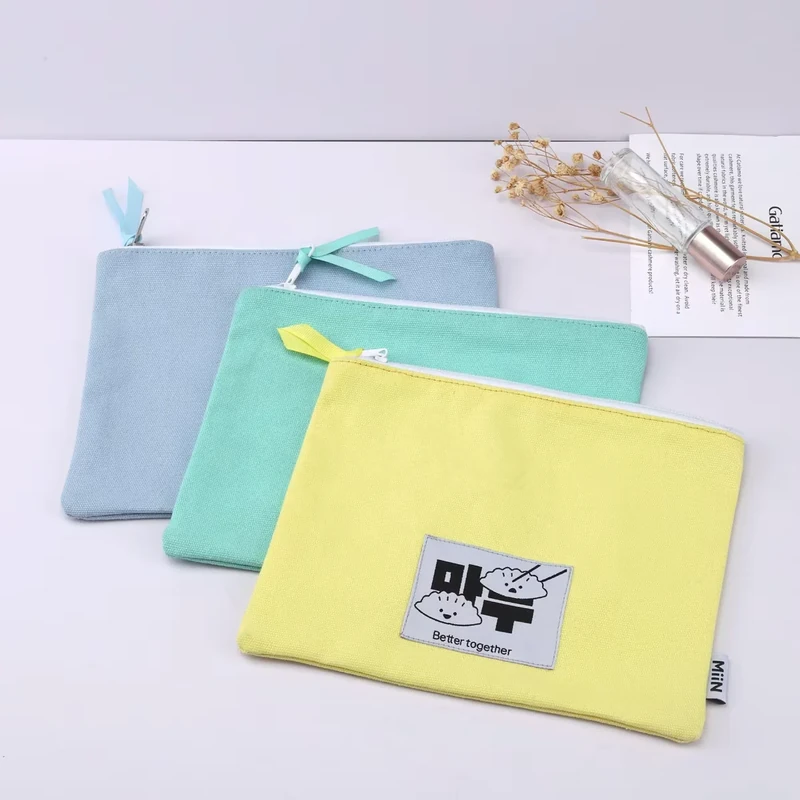 Flat zipper makeup pouches in blue, aqua, and yellow with fabric labels