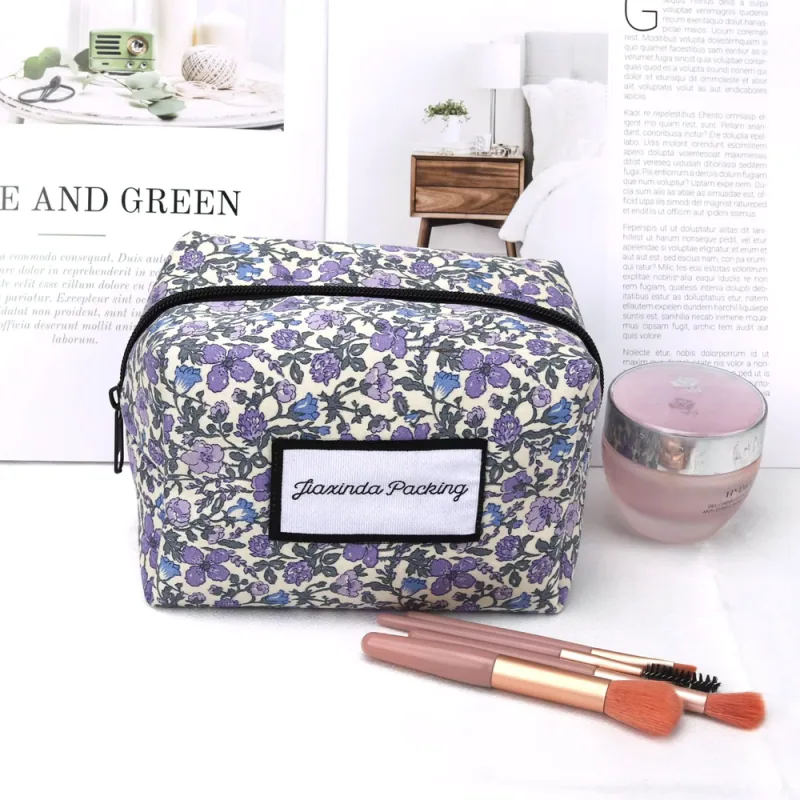 Boxy floral toiletry bag with a black zipper and front label
