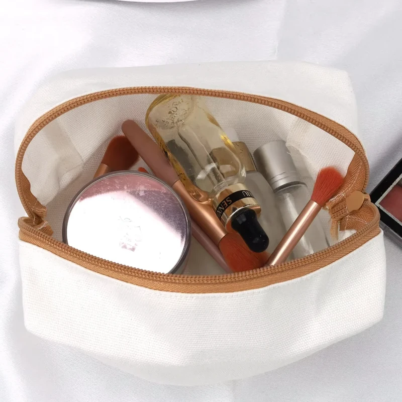 Open cream canvas cosmetic bag holding makeup brushes, bottles, and a compact