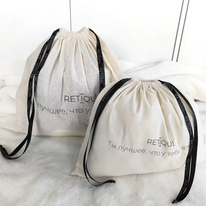 Two natural cotton dust bags with black ribbon drawstrings in different sizes