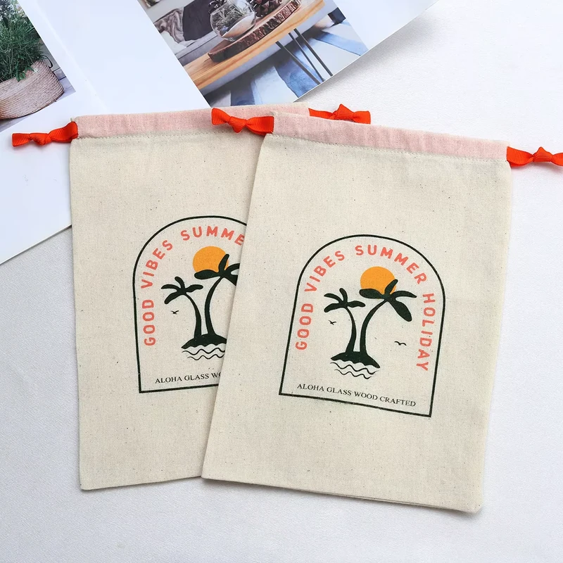 Two cotton drawstring pouches with multicolor printed artwork and orange ribbon ties