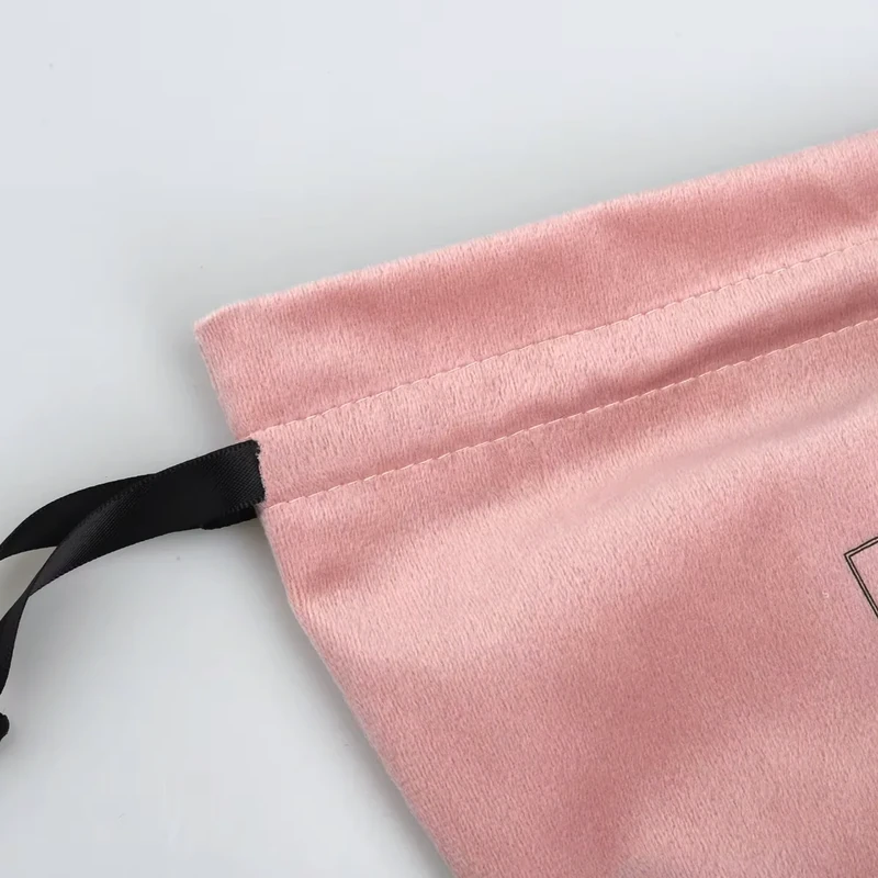 Close-up of pink velvet-style pouch fabric, stitching and a black ribbon tie