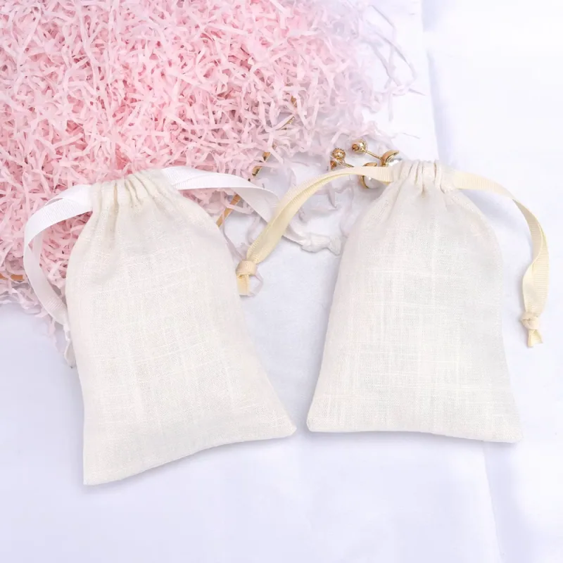 Two ivory woven drawstring gift pouches laid flat with white and pale yellow ribbon ties